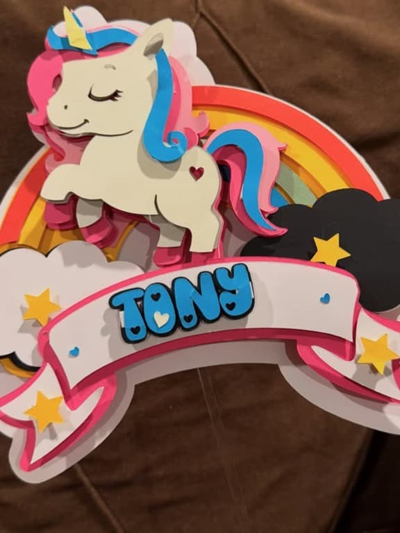 Unicorn cake topper with a rainbow and the name Tony