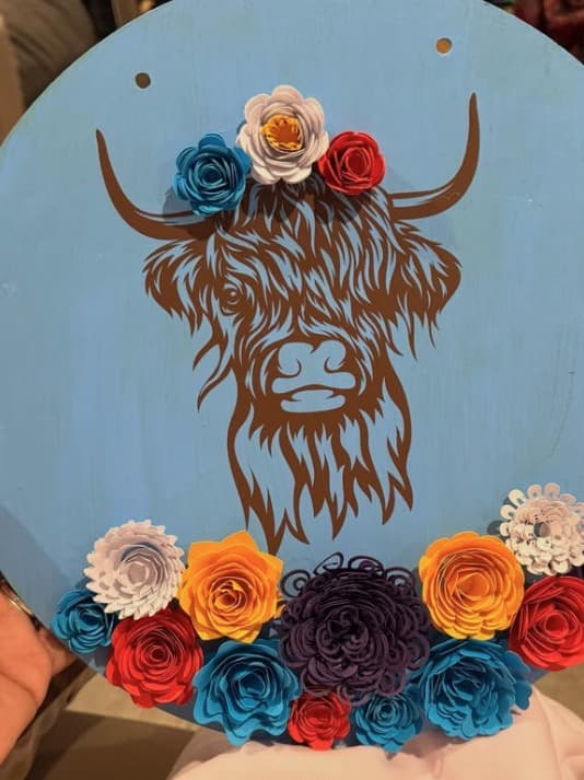 Light blue round door hanger with a highland cow and paper flowers