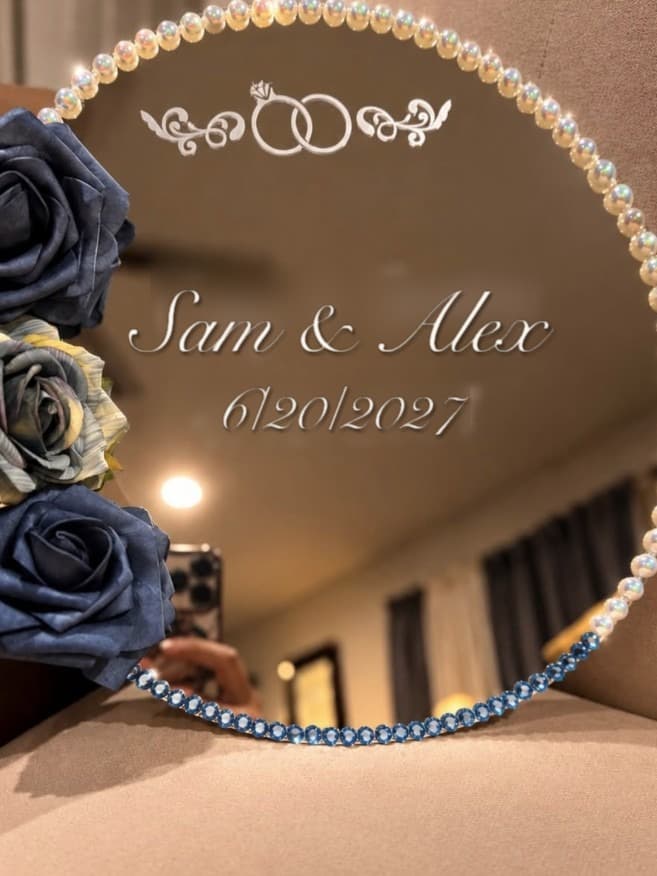 Round mirror with pearl trim, blue roses and sample names etched on the glass