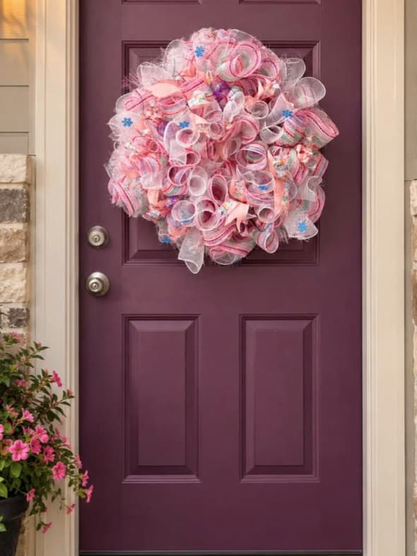 Pink deco-mesh wreath hanging on a purple front door